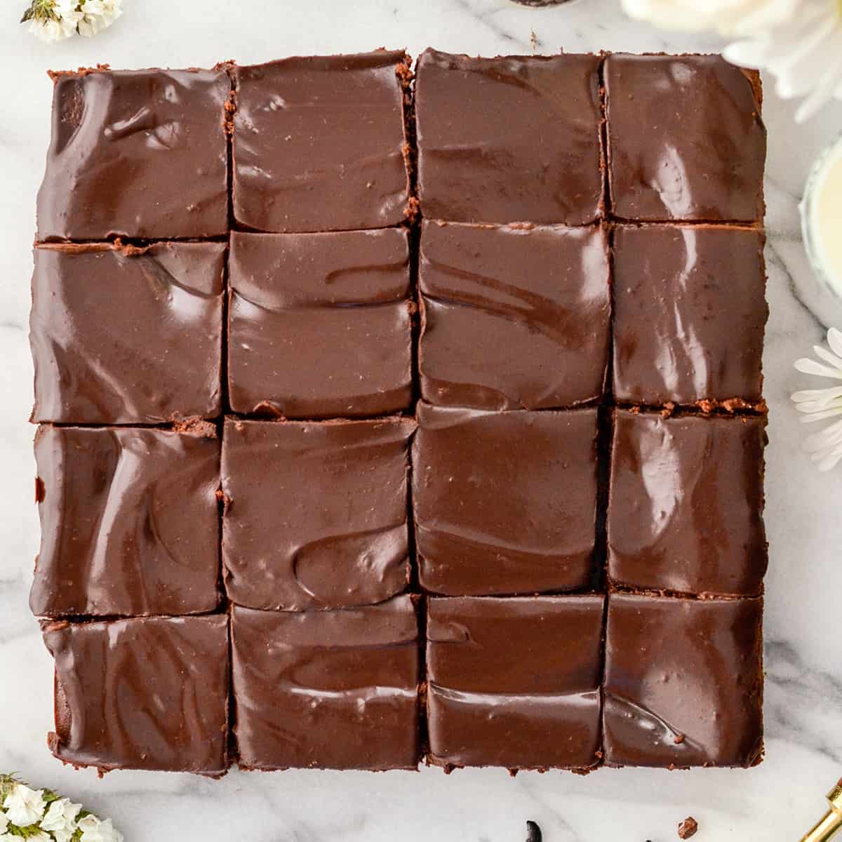 Overhead view of Healthy Greek Yogurt brownies cut into 16 square pieces. A shiny chocolate ganache with swirls. 