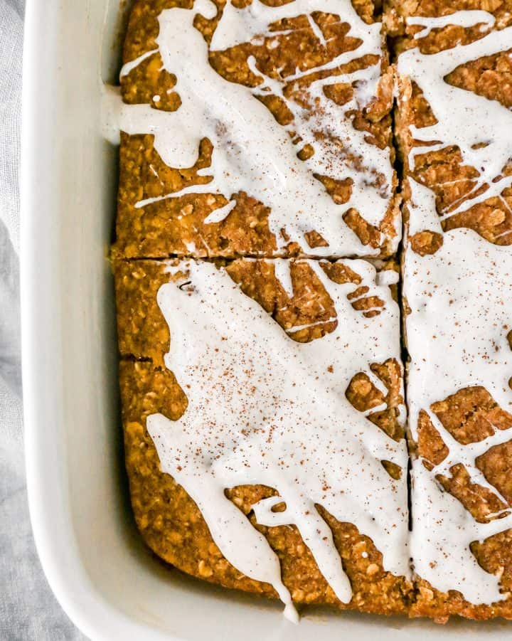 pumpkin baked oatmeal in a baking dish drizzled with cream cheese glaze