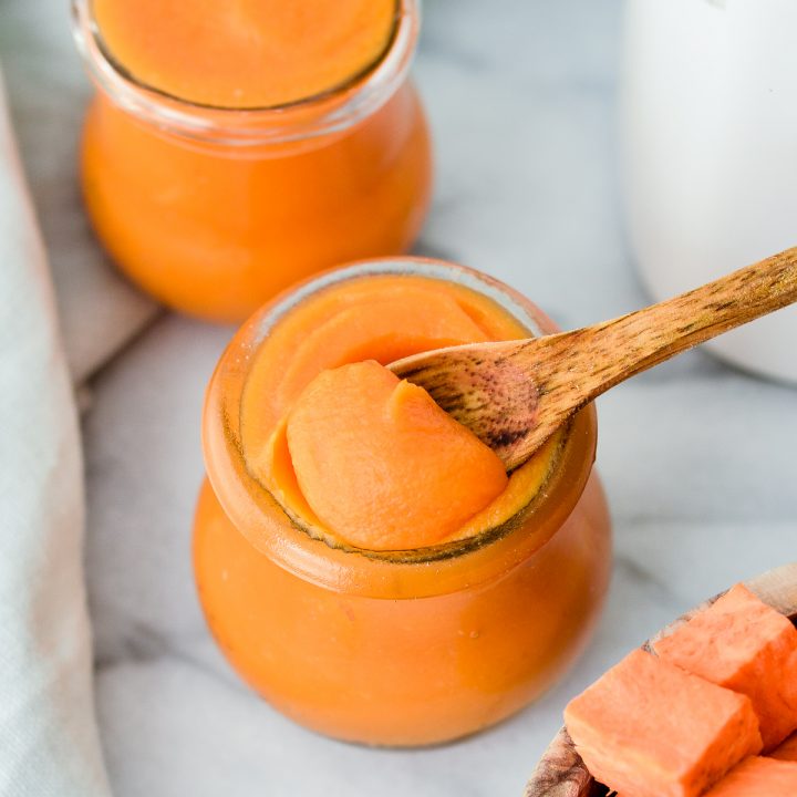 Overhead view of a spoon taking a scoop of Sweet Potato Baby Food out of a jar