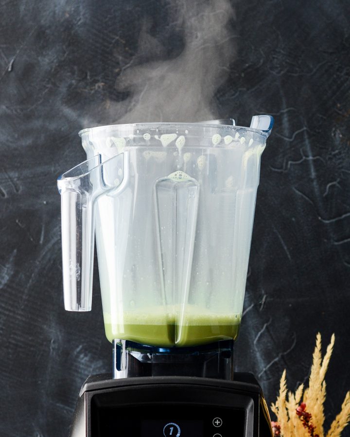 Front view of a Collagen Matcha Latte in a vitamix blender with steam pouring out of the top