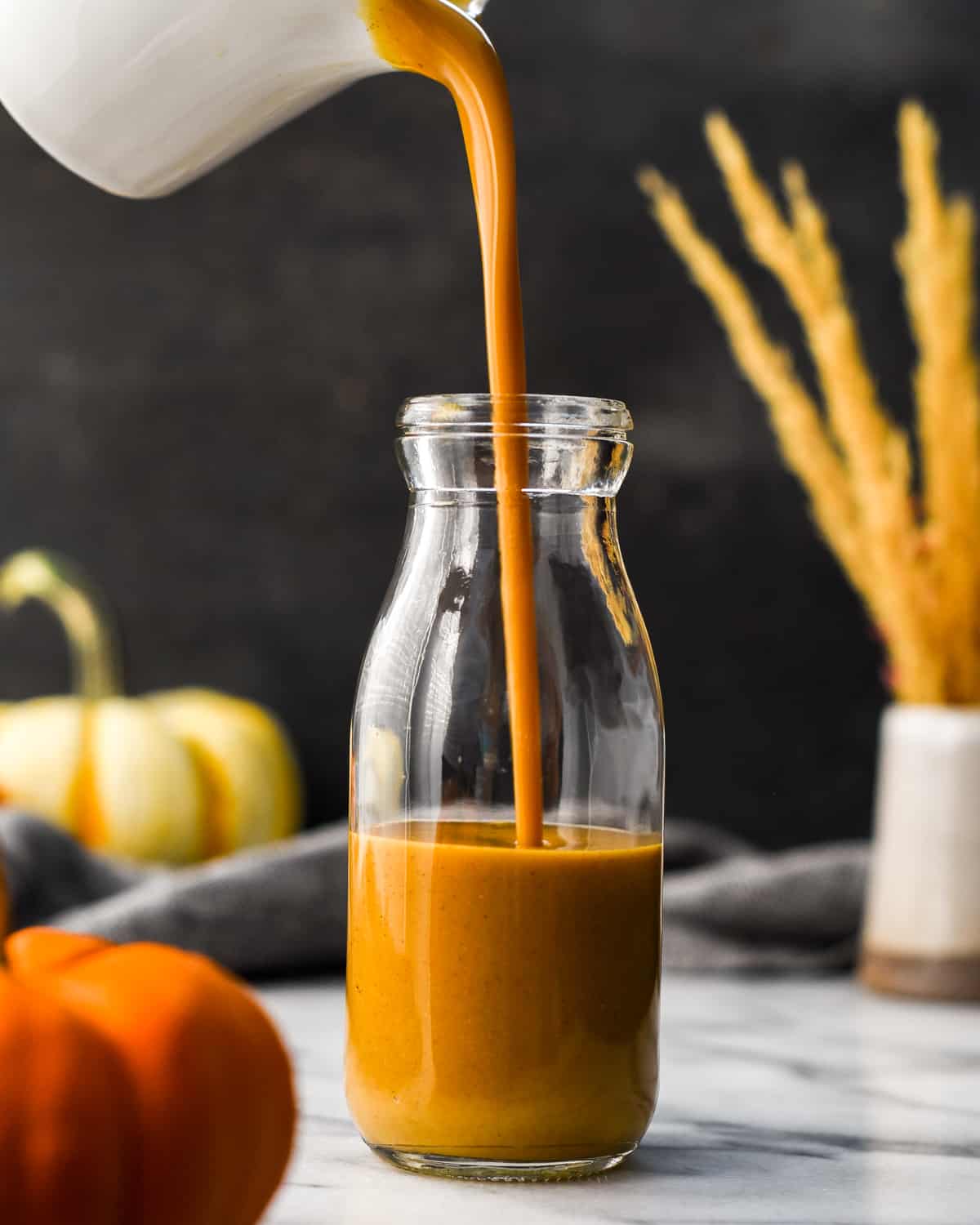 Front view of Pumpkin Coffee Creamer being poured into a glass bottle for storing