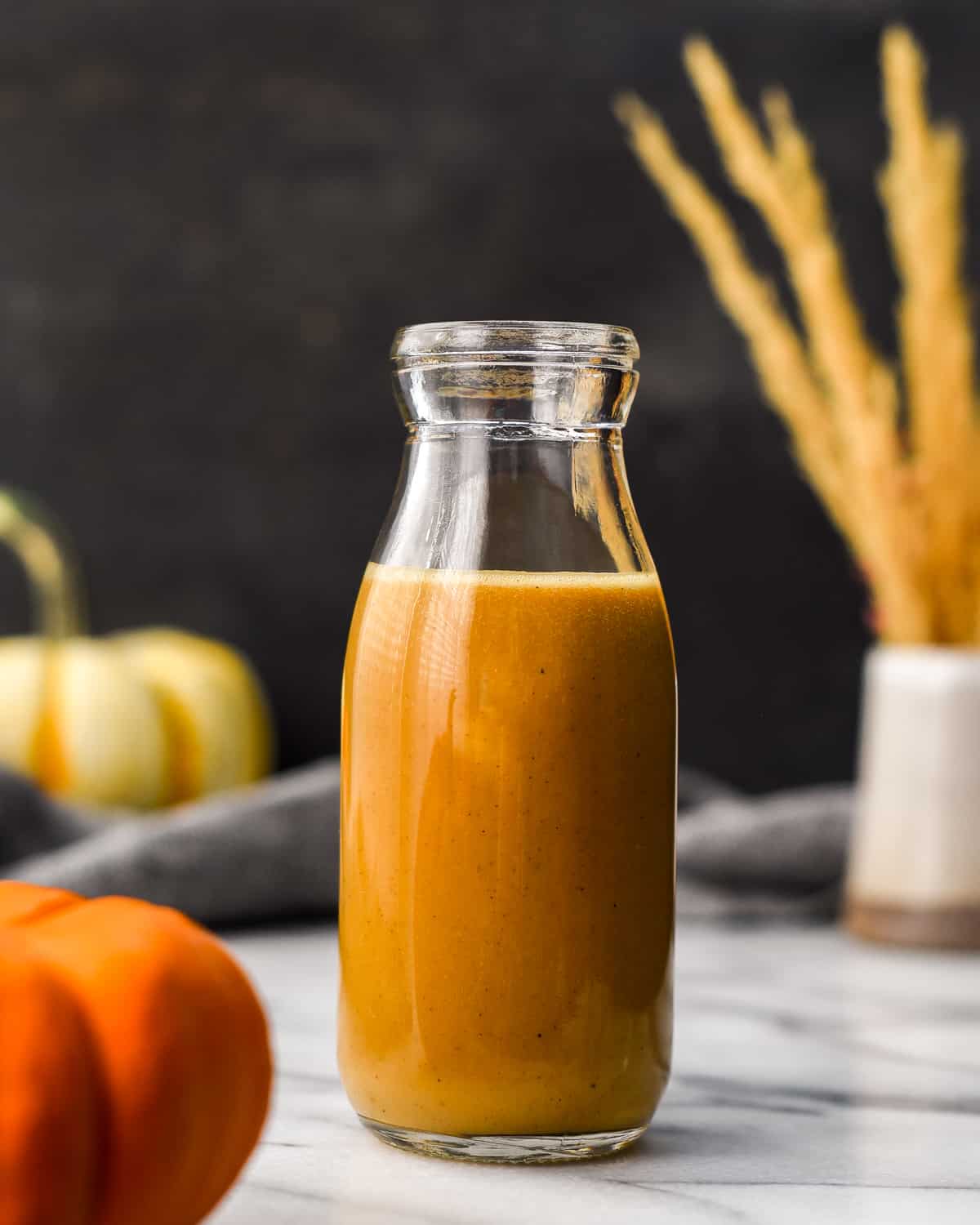 Front view of a glass bottle filled with Homemade Pumpkin Coffee Creamer 