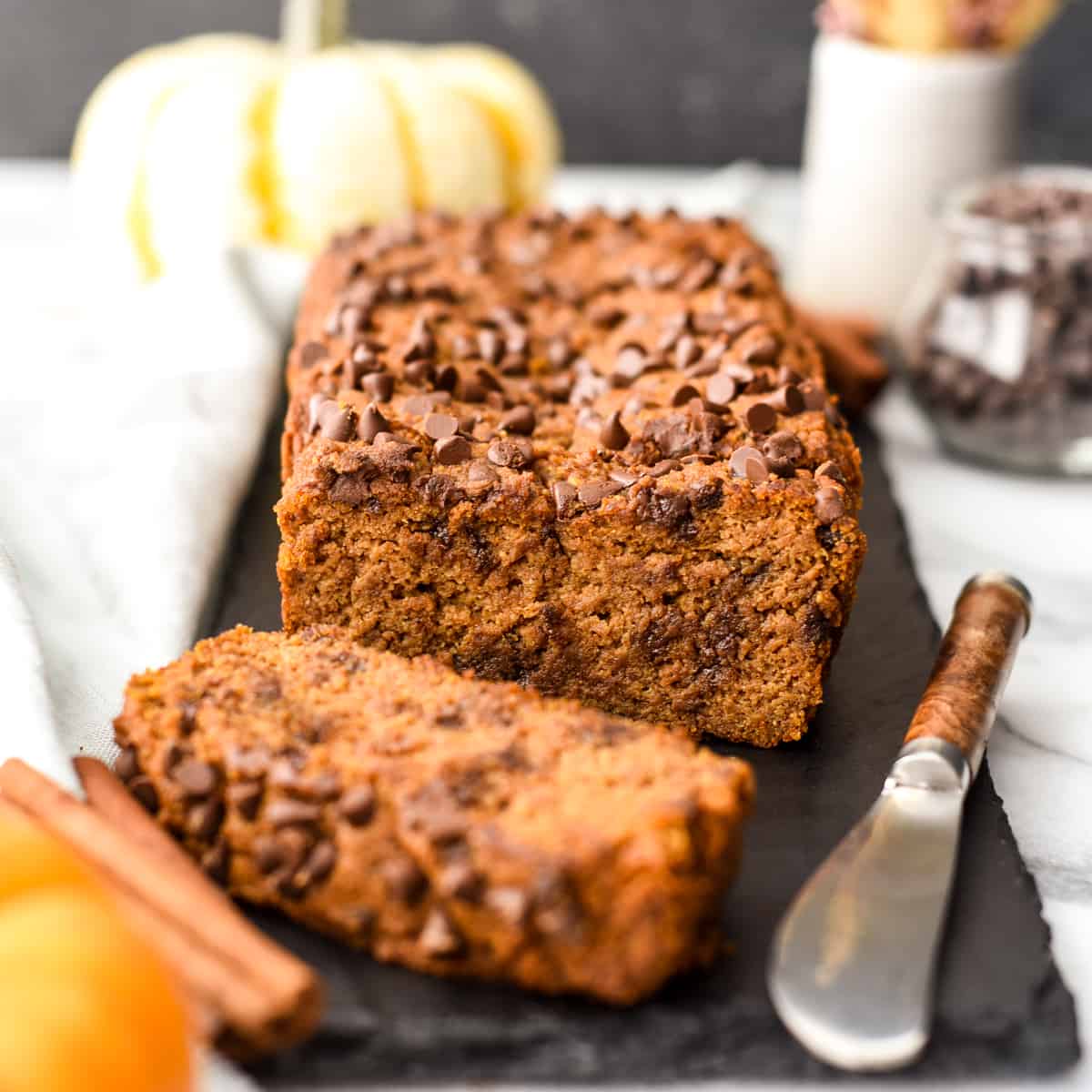 a loaf of chocolate chip paleo pumpkin bread with one slice cut out of it