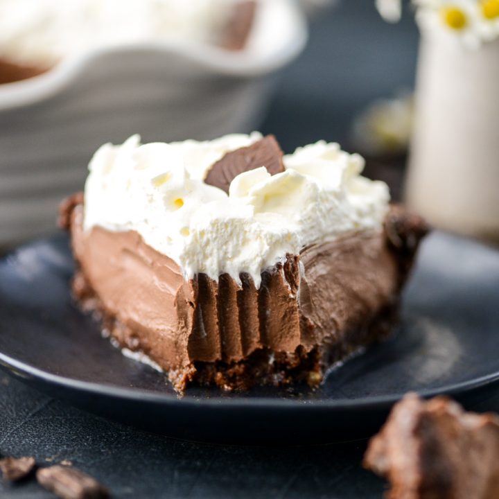 Front view of a slice of No-Bake Healthy Vegan Chocolate Pie on a plate with a bite taken out