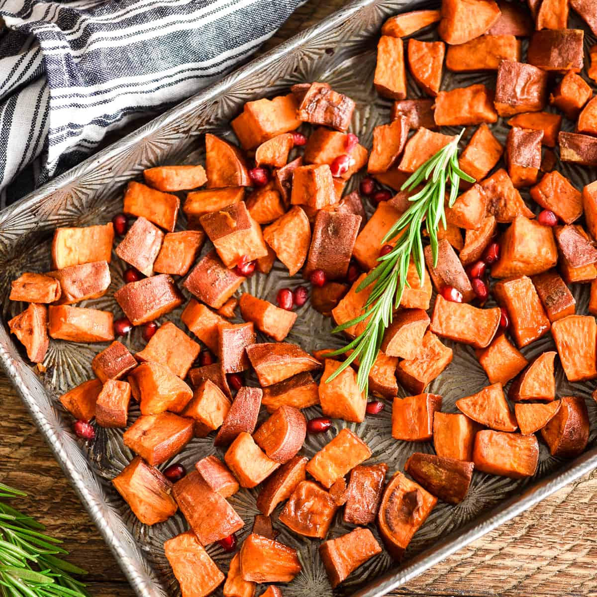 Overhead view of Cinnamon Roasted Sweet Potatoes garnished with rosemary and pomegranate seeds