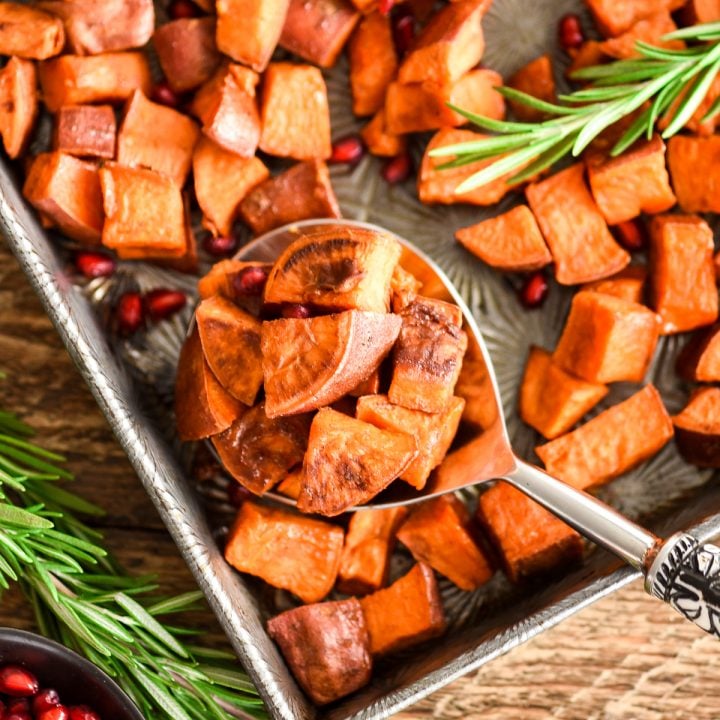 Overhead view of a pan of Cinnamon Roasted Sweet Potatoes with a spoon taking a scoop