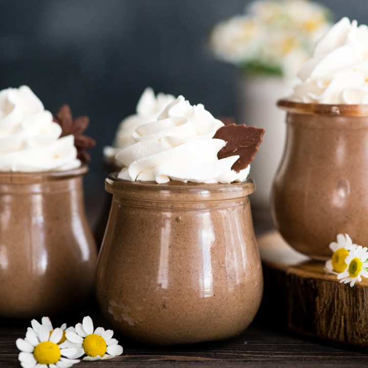 3 glass jars of chocolate peanut butter chia pudding topped with whipped cream
