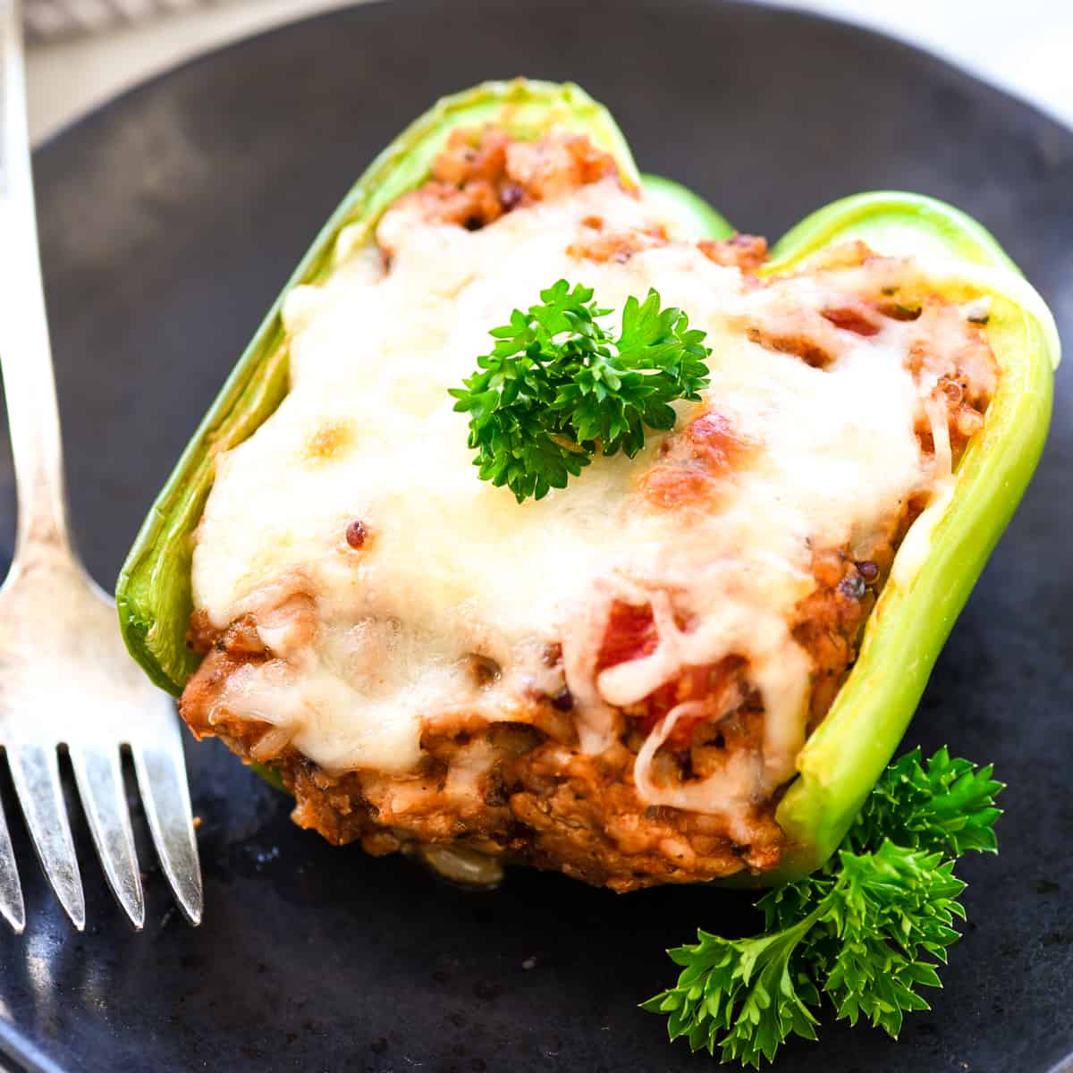 Front view of one Italian Ground Turkey Italian Stuffed Peppers on a plate with parsley and a fork