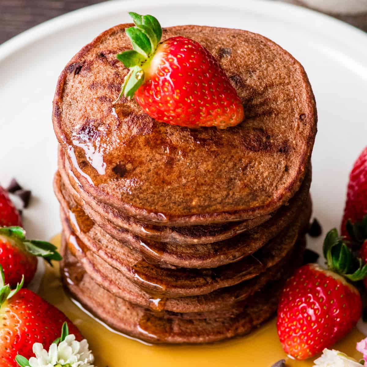 a stack of Healthy Chocolate Pancakes with syrup and strawberries
