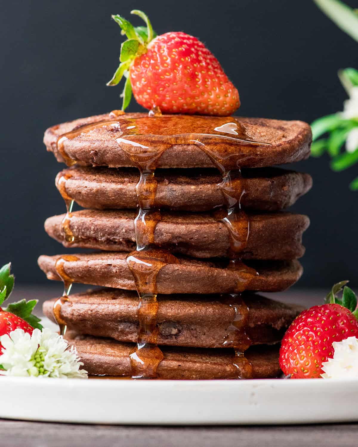 front view of a stack of 6 Healthy Chocolate Pancakes with syrup and strawberries