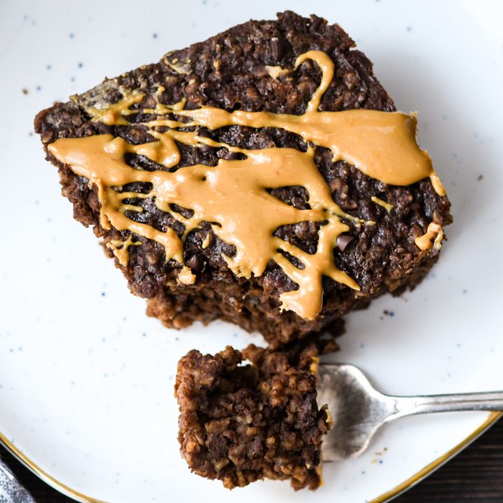 Overhead view of healthy Chocolate Peanut Butter Baked Oatmeal on a plate with a bite taken out of it on a fork next to it