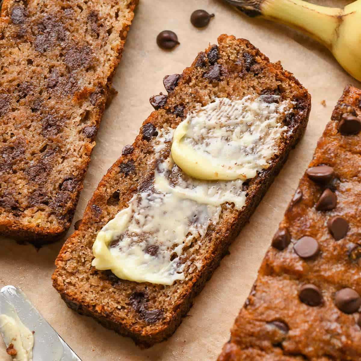 a slice of chocolate chip Paleo Banana Bread with butter spread on top