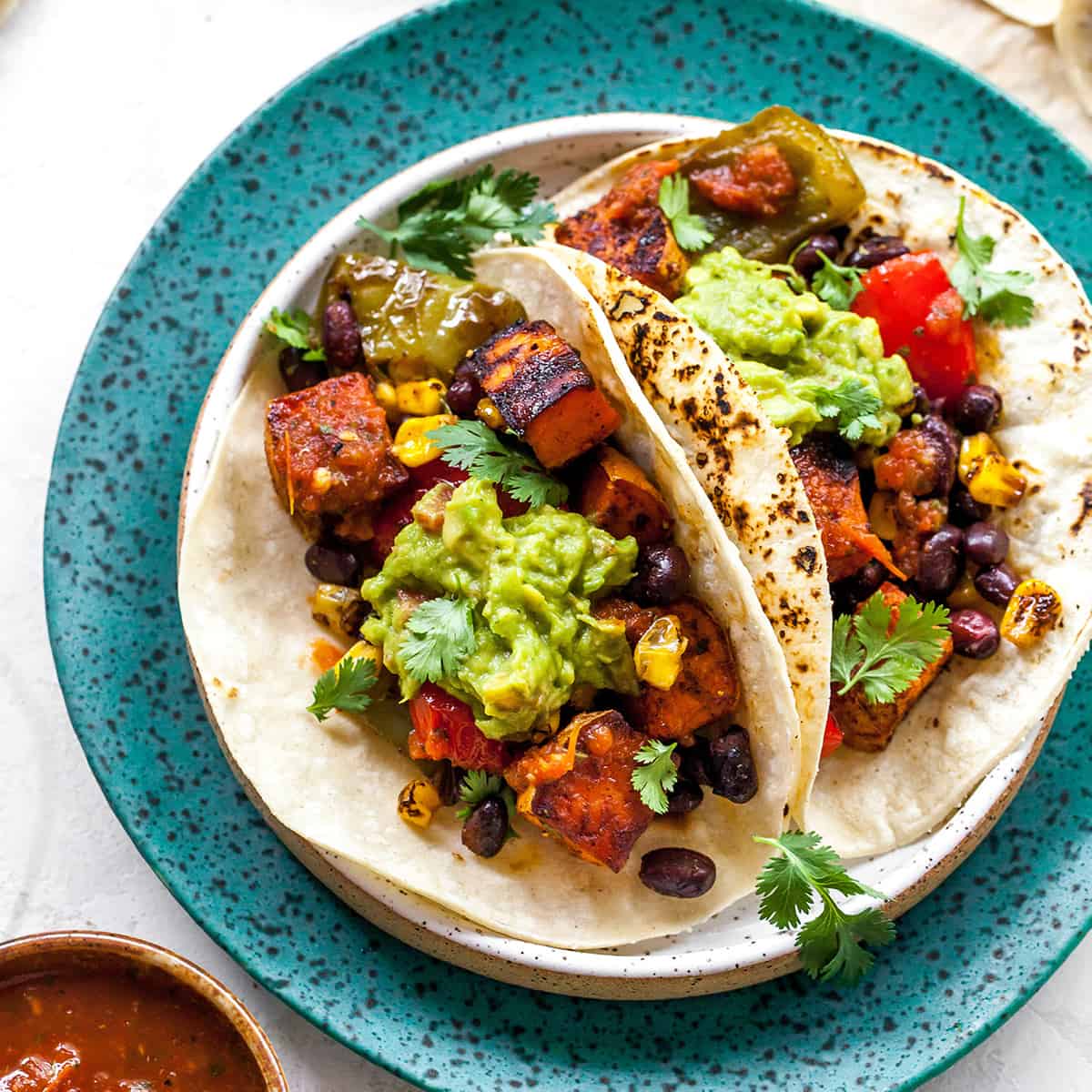 overhead view of three black bean sweet potato tacos with guacamole on a plate