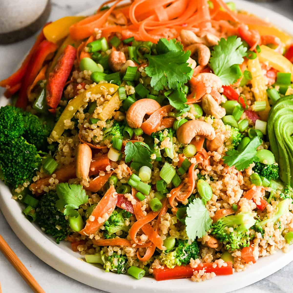 asian quinoa salad on a plate garnished with cilantro and cashews