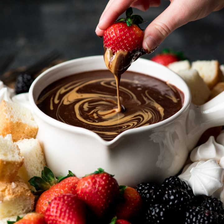 a strawberry being dipped into chocolate peanut butter fondue