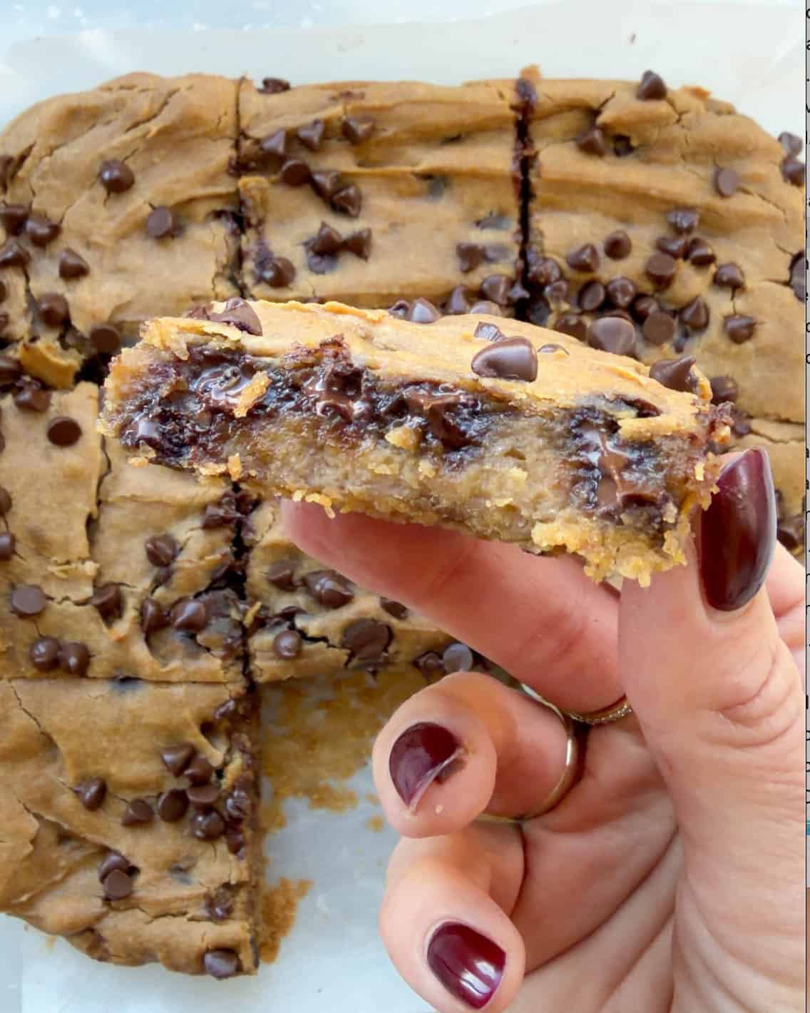 a hand holding one chickpea blondie over the other 8 cut out chickpea blondies