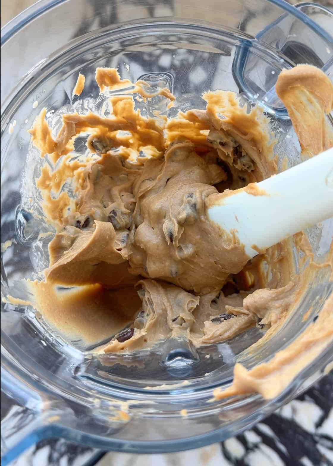 a spatula stirring chickpea blondies batter with chocolate chips inside a blending container