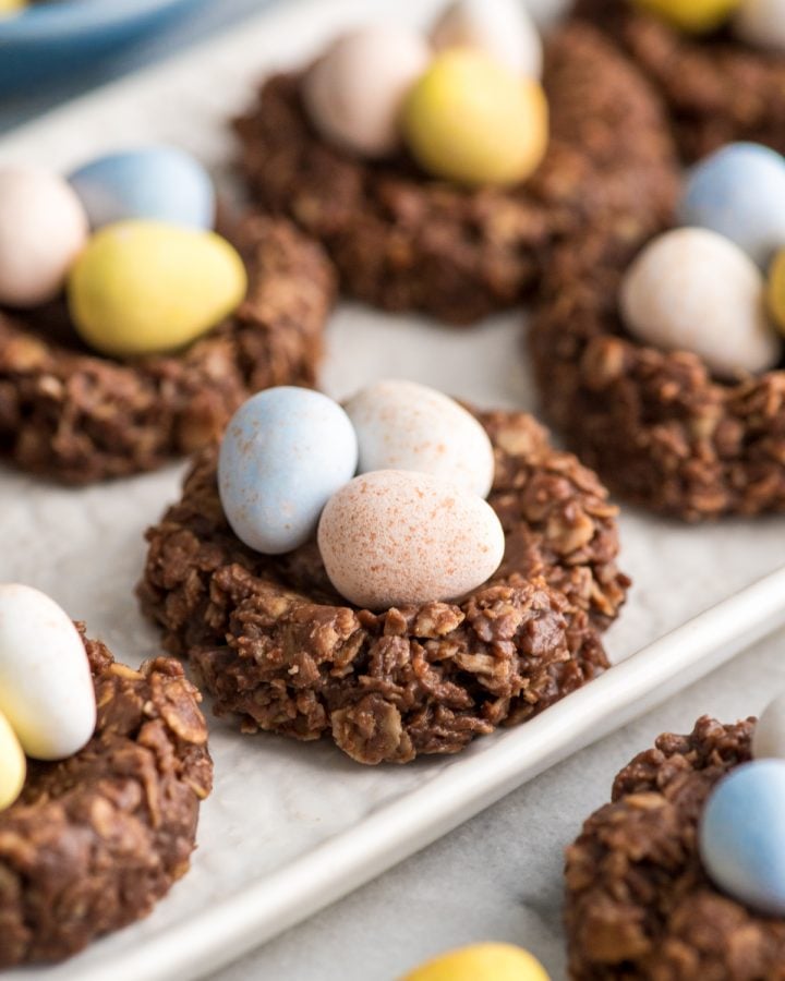 Side view of an oval plate of no-bake chocolate peanut butter easter nest cookies with chocolate eggs on an oval platter