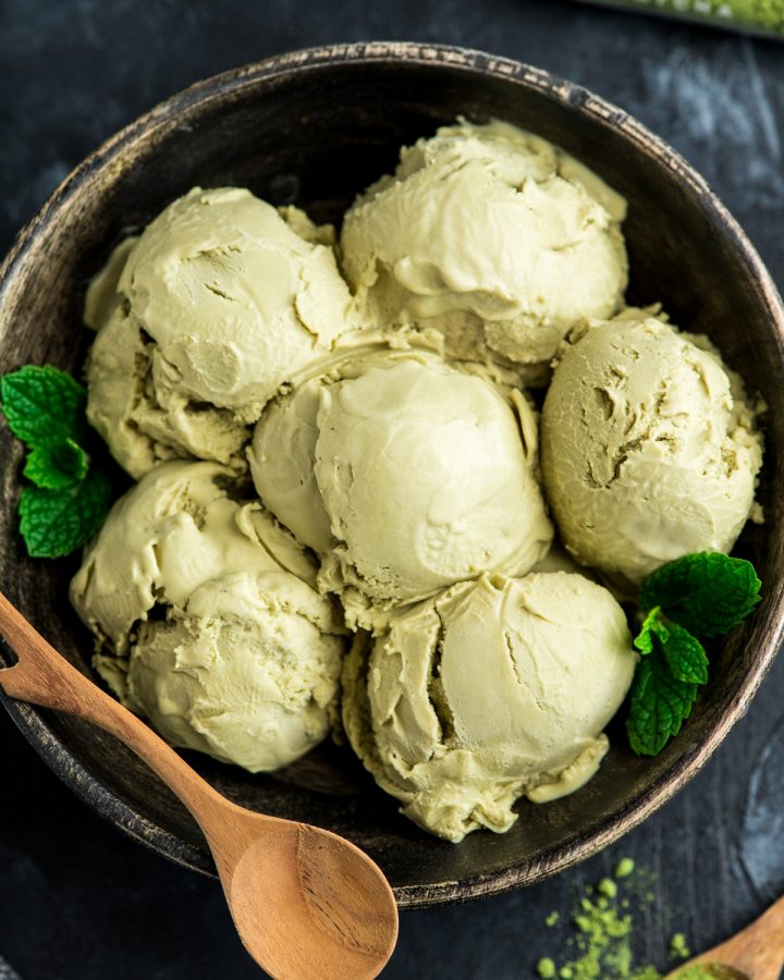 close up overhead view of 6 scoops of dairy-free matcha ice cream in a wooden bowl with fresh mint leaves as a garnish