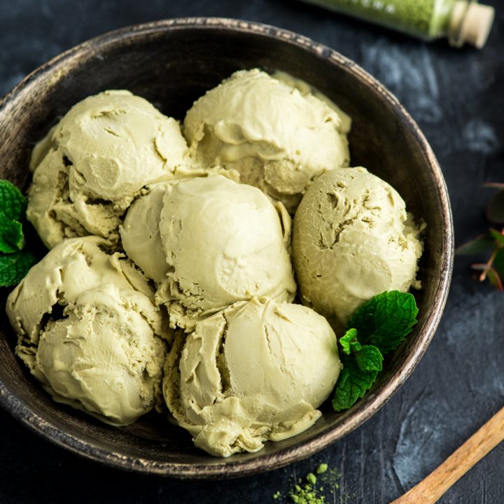  6 scoops of dairy-free matcha ice cream in a wooden bowl with fresh mint leaves as a garnish