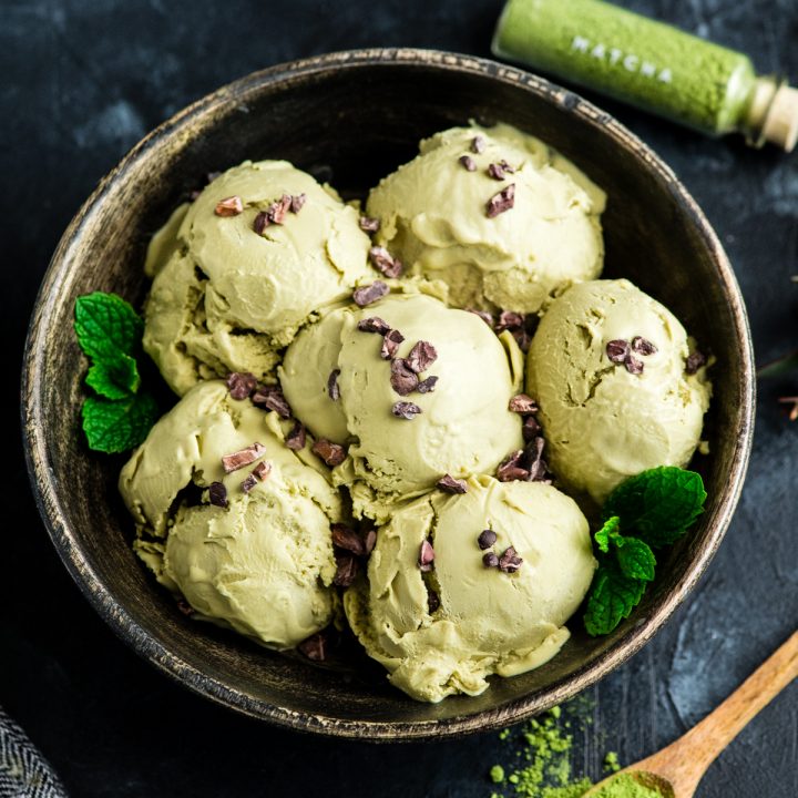 Overhead view of a bowl with 6 scoops of dairy-free matcha ice cream sprinkled with cocoa nibs 