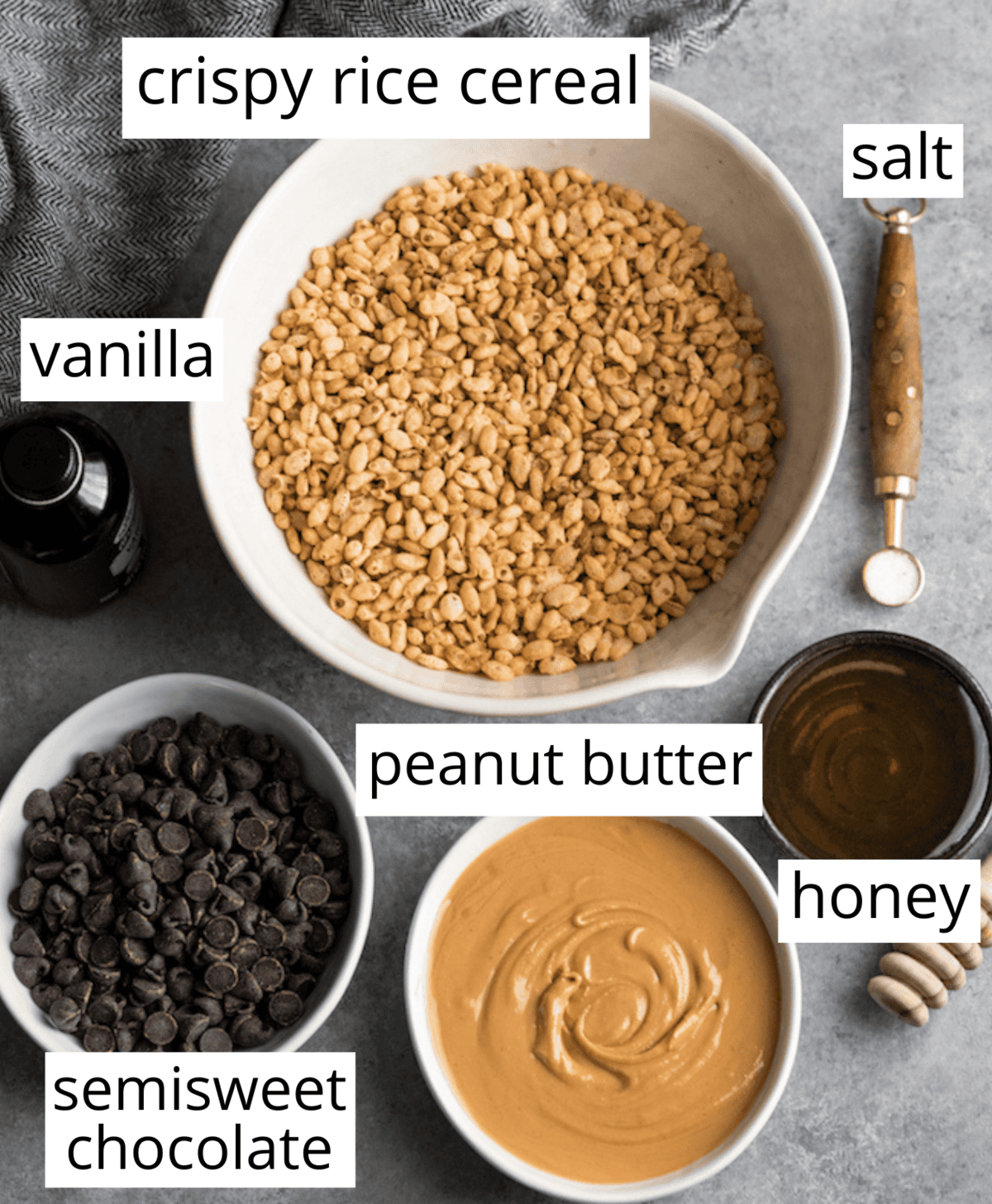 These Healthy Peanut Butter Rice Crispy Treats are made with only 6 good-for-you ingredients and come together in minutes! There are no marshmallows or corn syrup in this recipe! They are the perfect easy, no-bake, gluten-free dessert to satisfy your chocolate peanut butter cravings! #glutenfree #dairyfree #veganfriendly #vegan #dessert #ricecrispytreats #snack #refinedsugarfree Overhead view of the ingredients in this healthy peanut butter rice crispy treat recipe in bowls and labeled like peanut butter, honey, vanilla, salt, semisweet chocolate and crispy rice cereal.