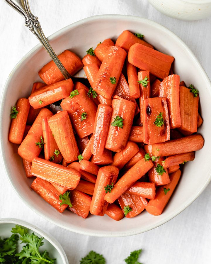 honey glazed carrots in a bowl garnished with carrot greens. 
