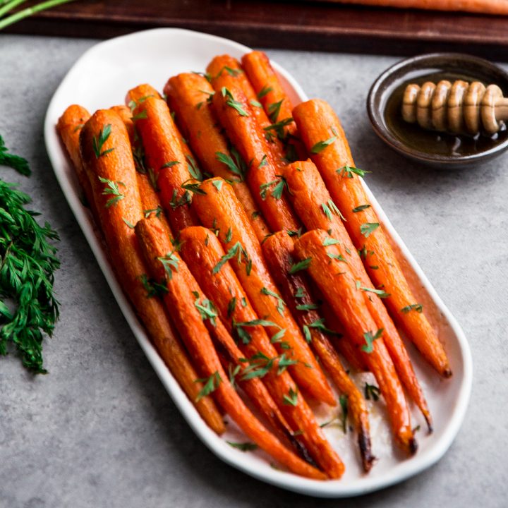 Side view of honey roasted carrots on an oval platter