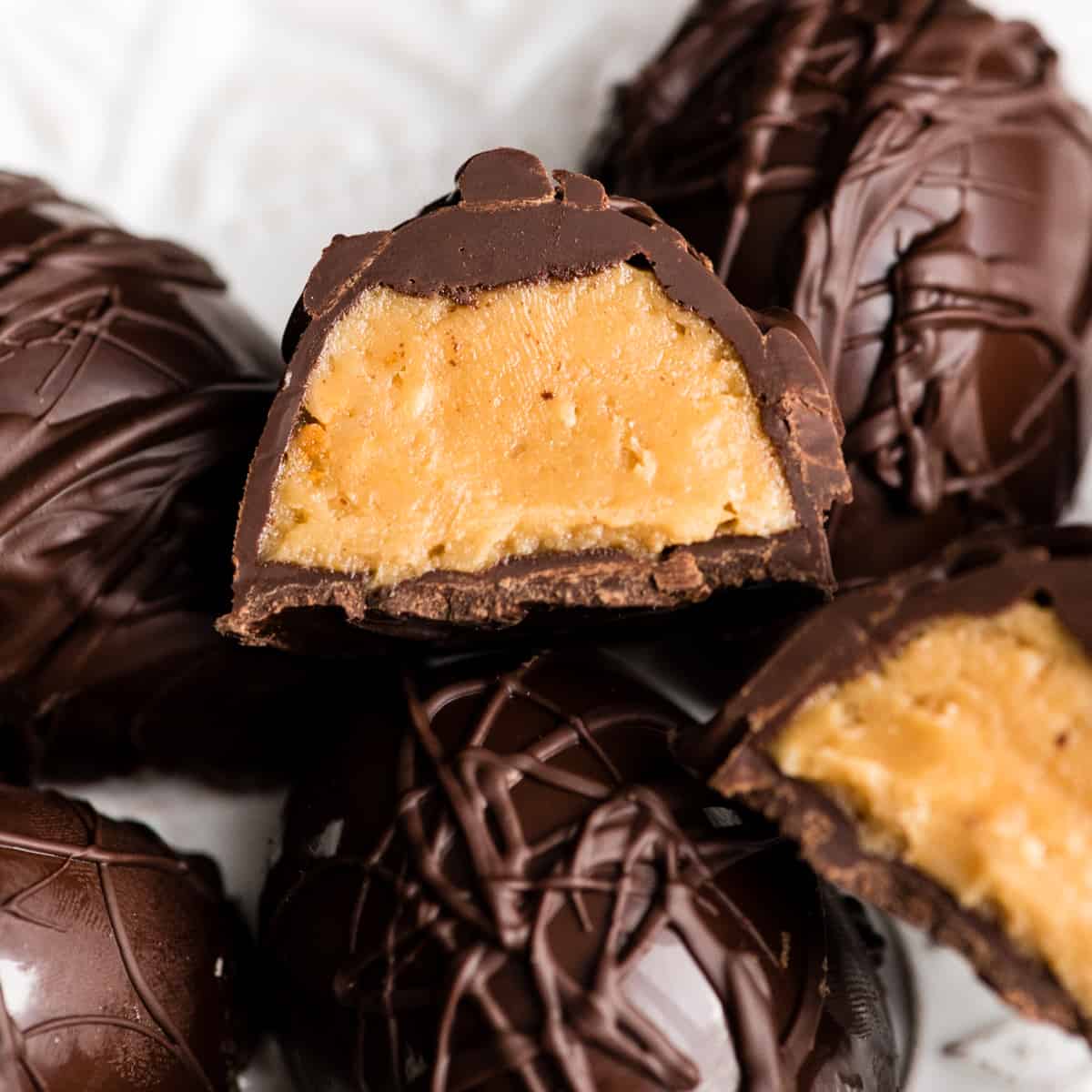 Close-up overhead view of the inside one vegan peanut butter egg cut in half. The halves are resting on 4 other uncut vegan peanut butter eggs 