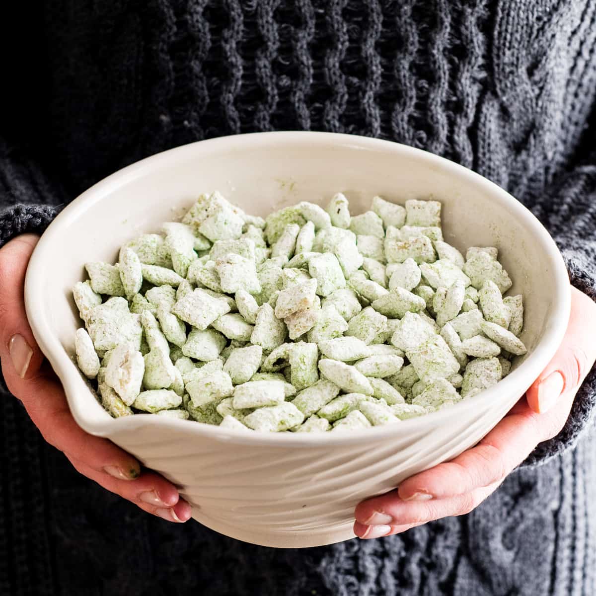 Hands holding a bowl of white chocolate matcha puppy chow