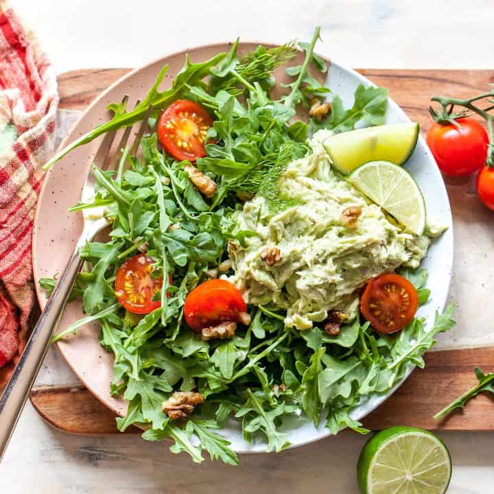 Avocado Chicken Salad on top of salad with arugula and tomatoes