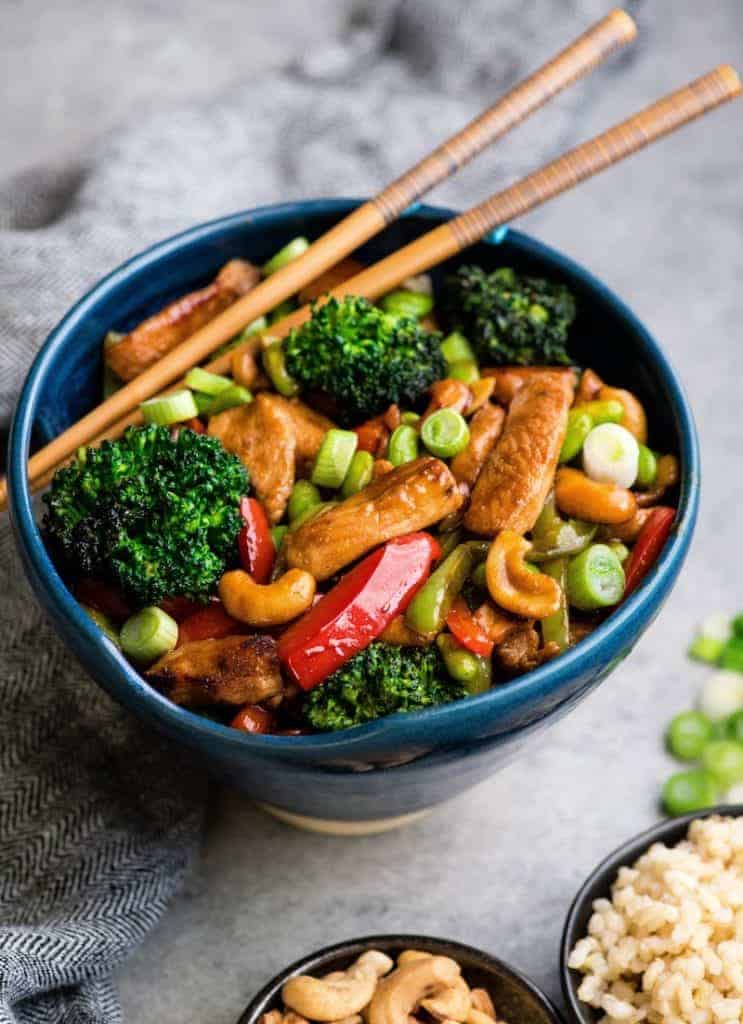 Overhead view of Cashew Chicken Stir Fry Recipe in a blue bowl with chopsticks 
