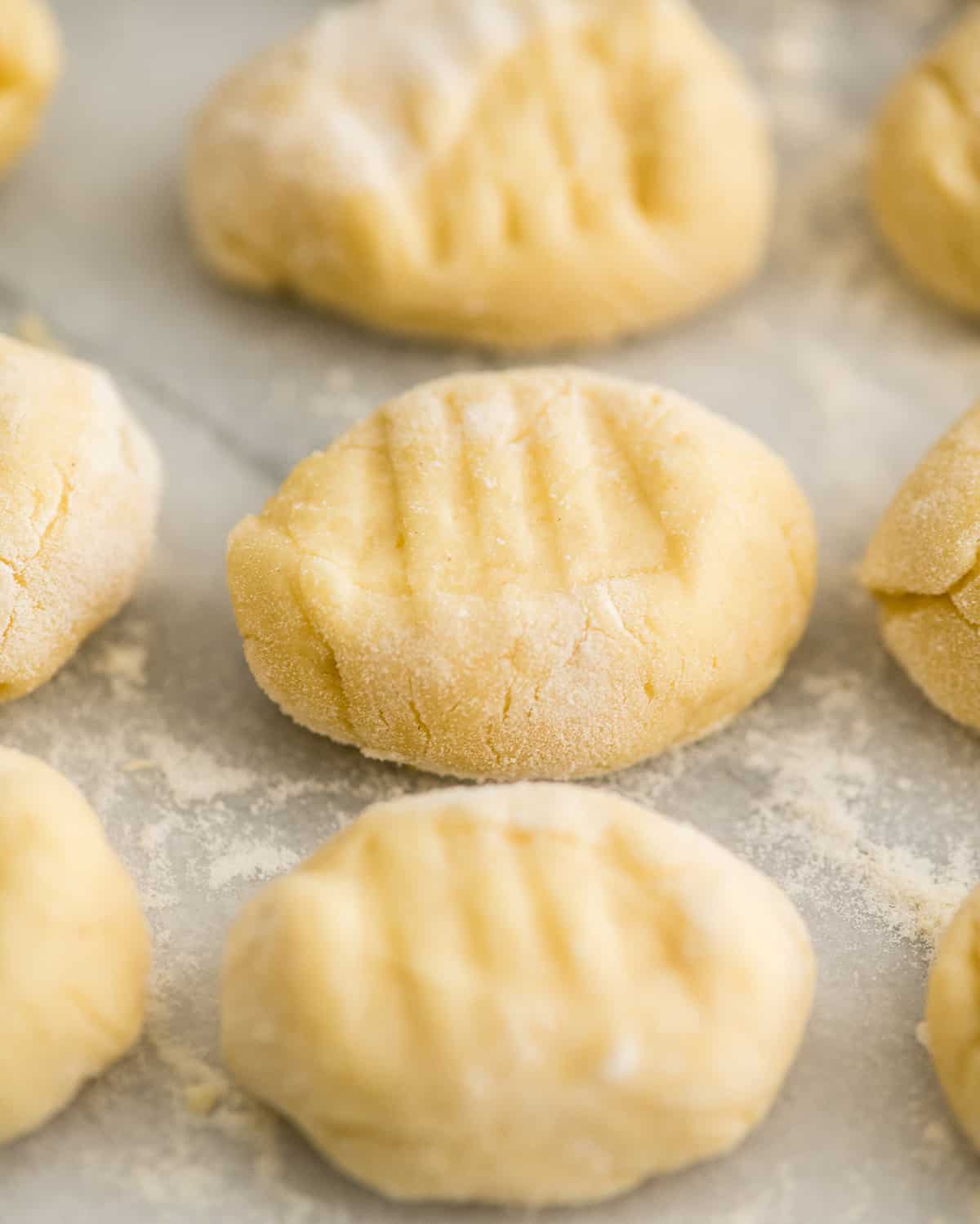 Up close front view of an uncooked homemade potato gnocchi in rows with after being pressed with a fork 
