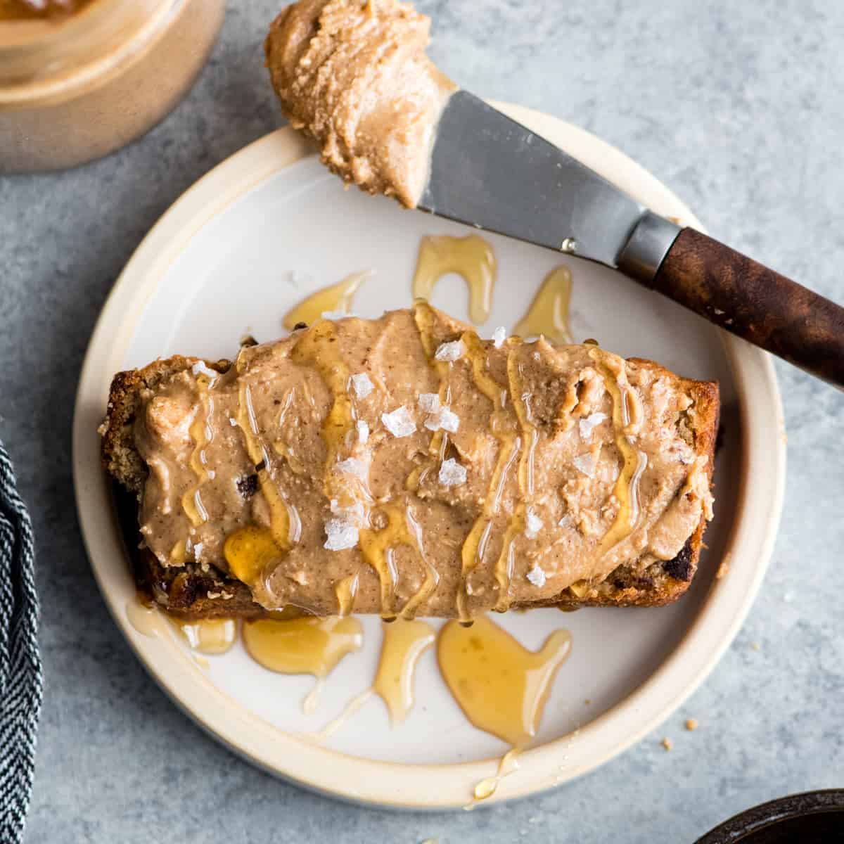 vanilla almond butter spread on a piece of banana bread drizzled with honey and sea salt