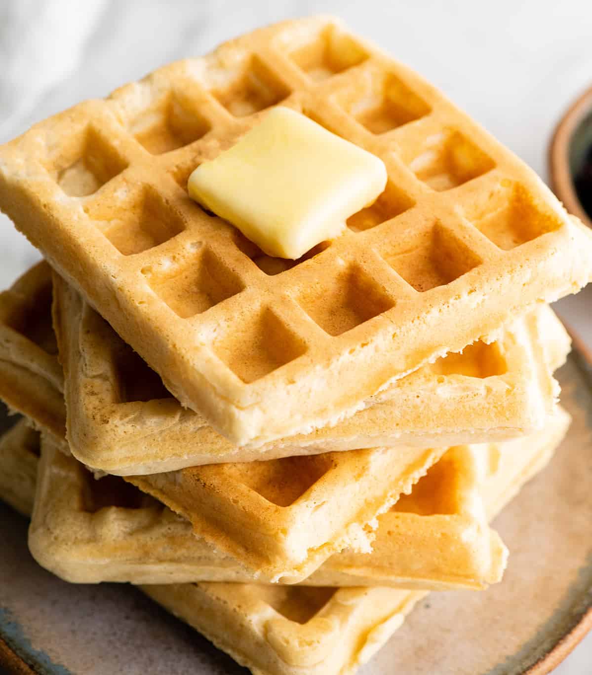 front view of a stack of 5 waffles with butter melting on top