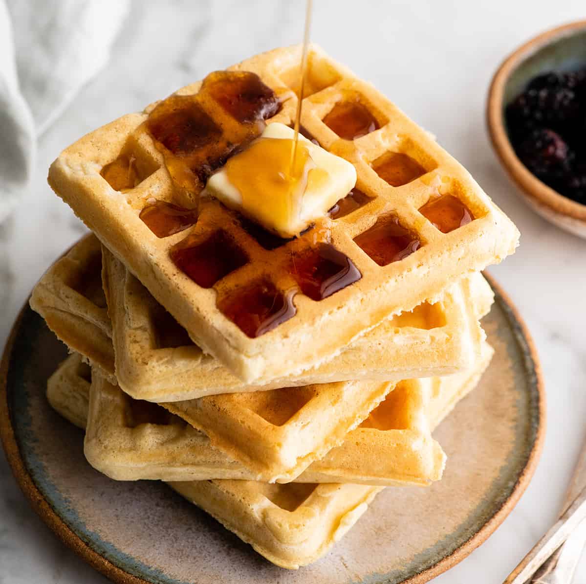 stack of 5 waffles with butter and syrup