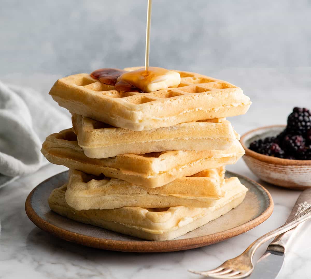 syrup being poured onto a stack of the best waffle recipe