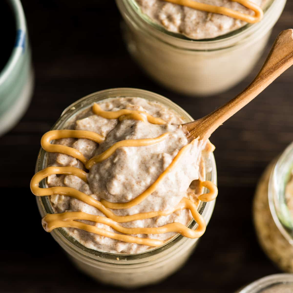 Overhead view of a spoon scooping some Peanut Butter Chia Overnight Oats out of a glass jar 