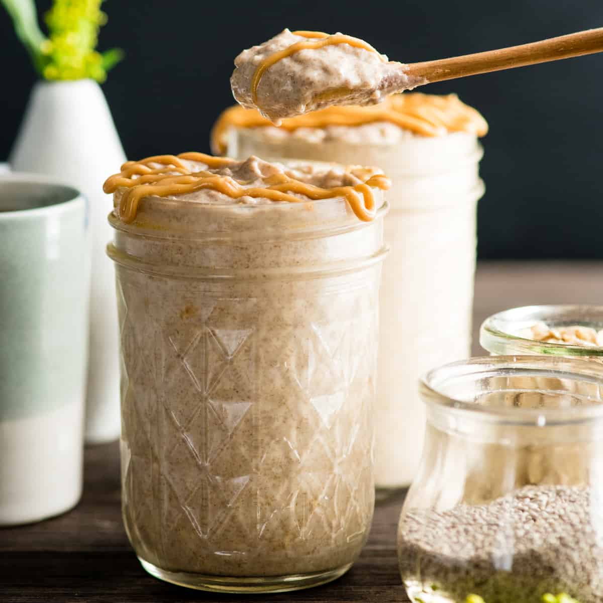 a spoon taking a bite out of a jar of Peanut Butter Overnight Oats