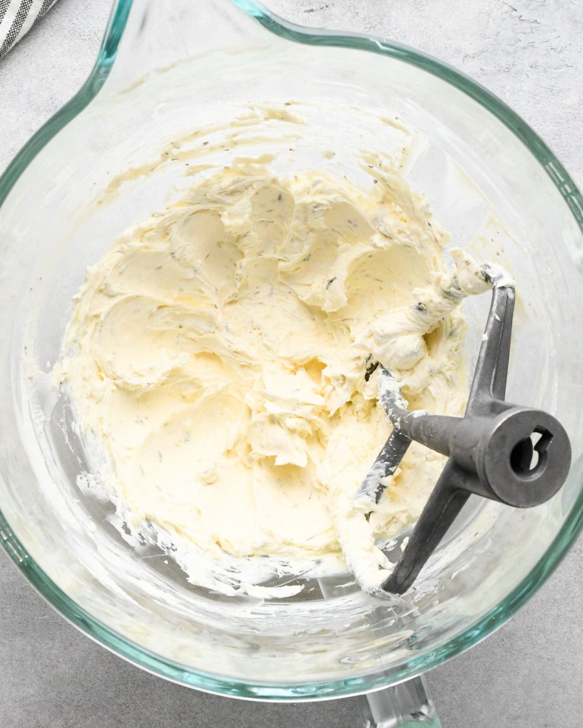 beaten seasoned cheese mixture in a glass mixing bowl with a paddle attachment, made to be the bottom layer for  layered Greek dip