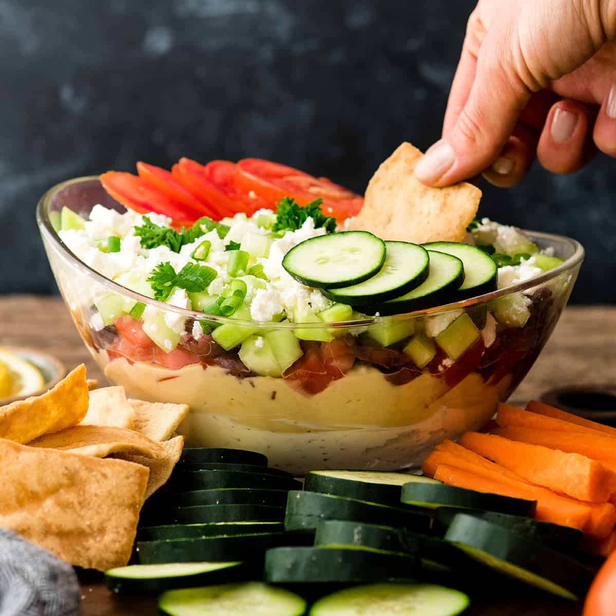 photo of a hand dipping a pita chip into a bowl of Greek dip