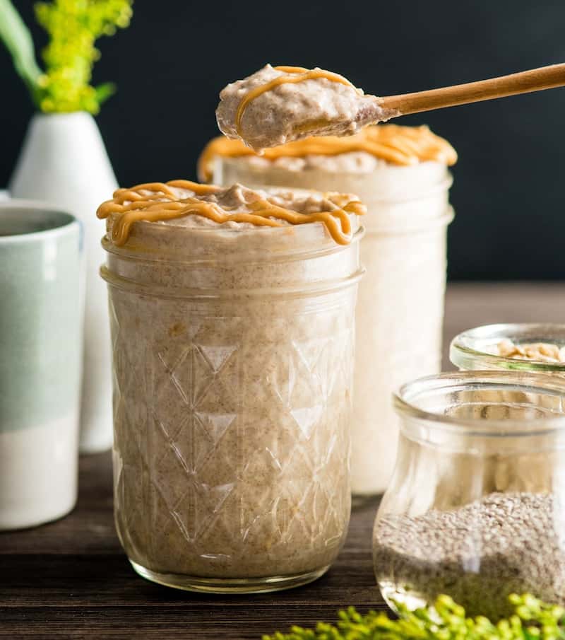 Front view of a spoon holding a scoop of Peanut Butter Chia Overnight Oats over a glass jar