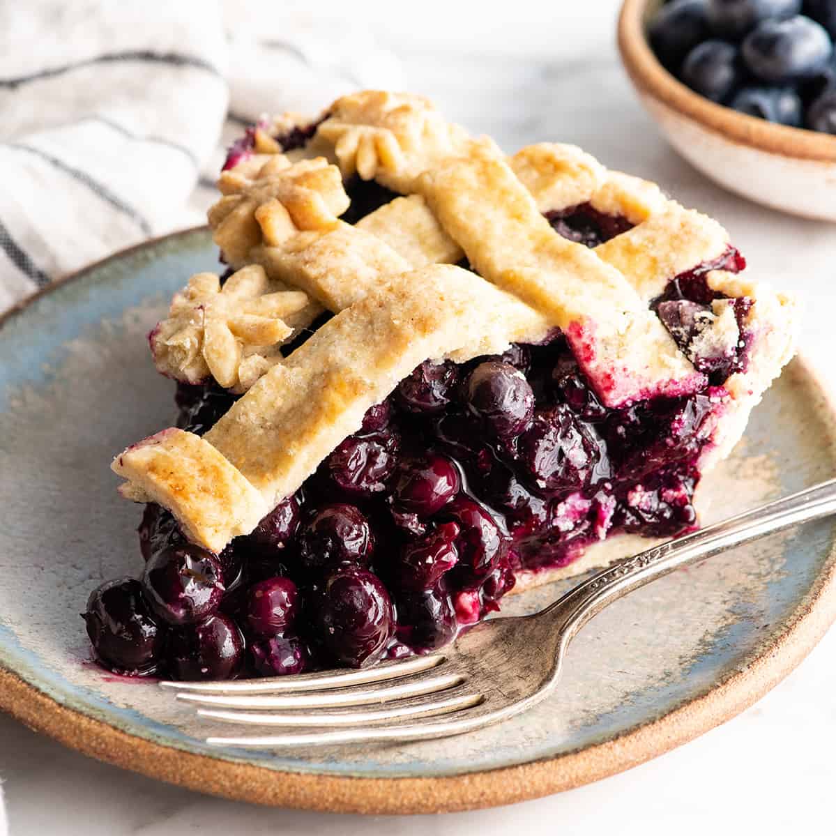 front view of a slice of blueberry pie on a plate