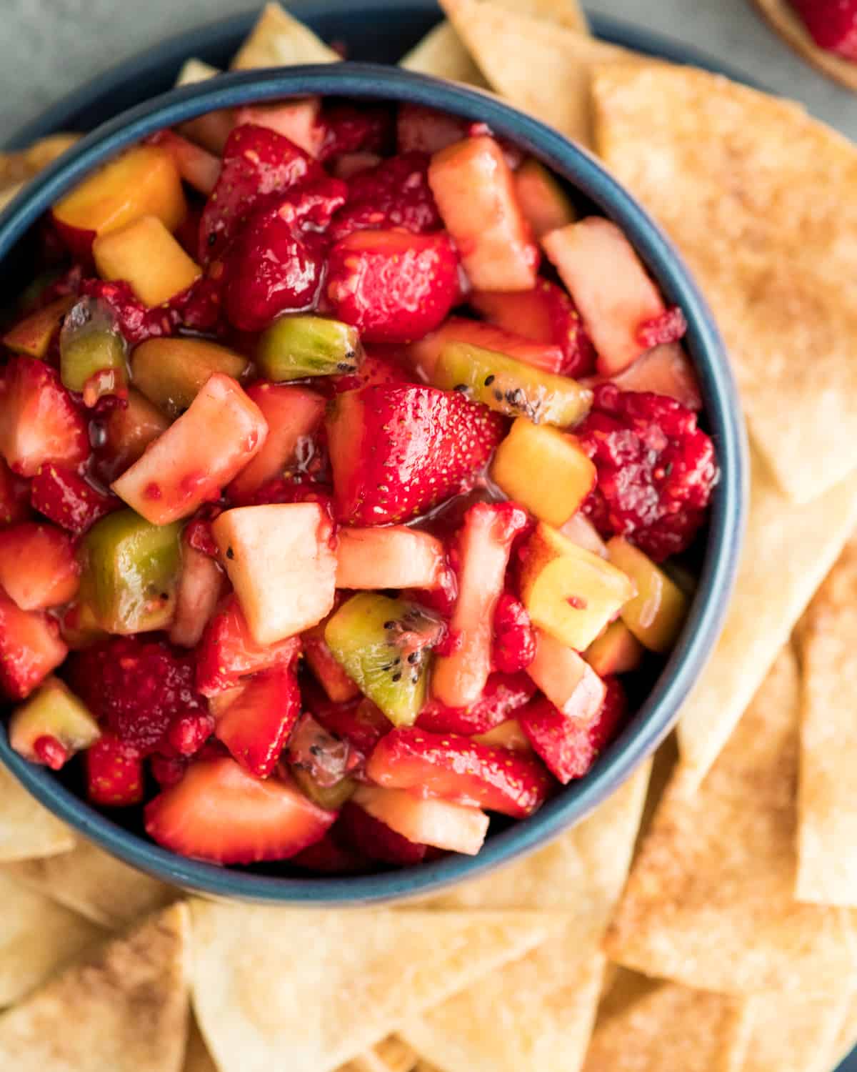 Overhead view of a bowl of fruit salsa with surrounded by cinnamon chips