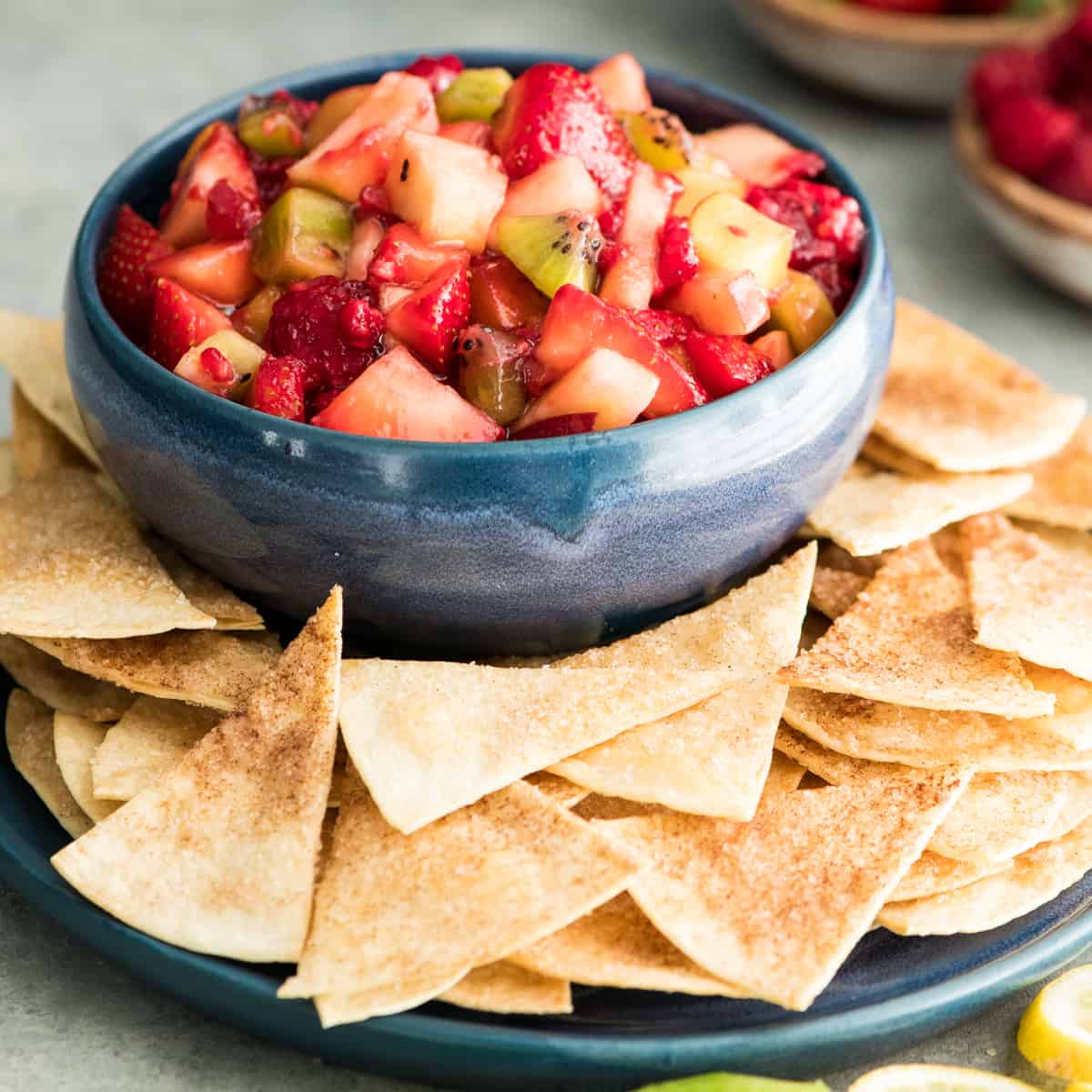 Front view of a bowl of Fruit Salsa Recipe with cinnamon chips on a serving plate 