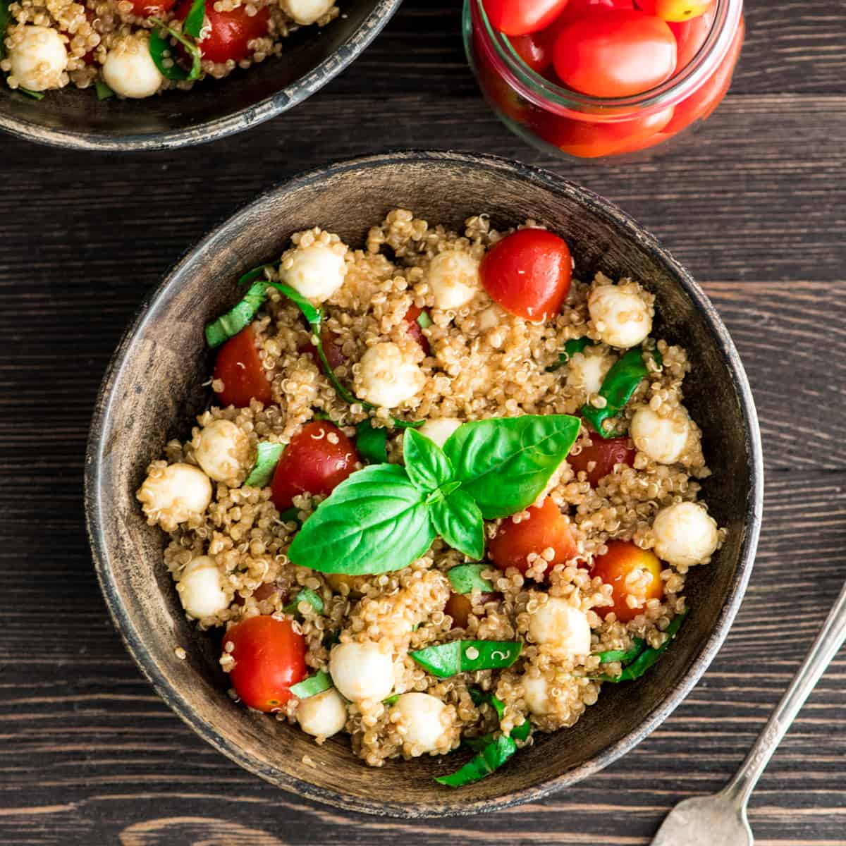 Overhead view of a bowl of Balsamic Caprese Quinoa Salad garnished with fresh basil