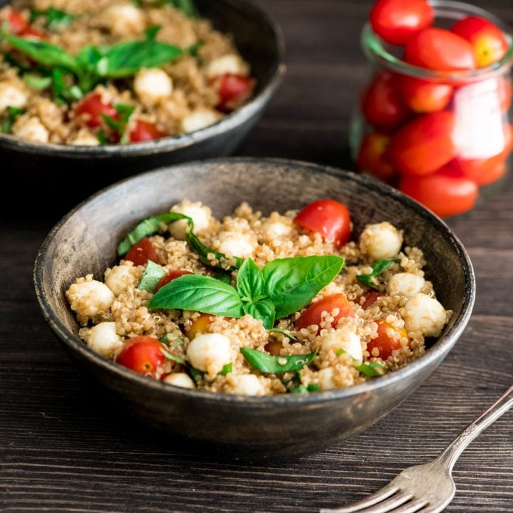 front view of a bowl of Balsamic Caprese Quinoa Salad garnished with fresh basil