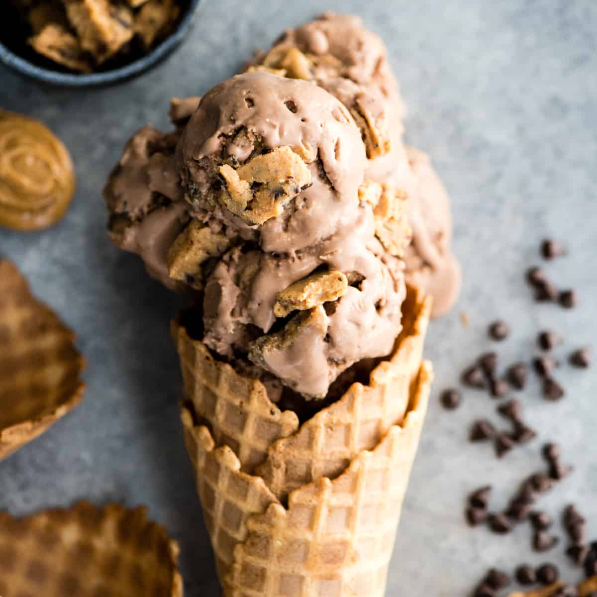 Up close overhead view of four scoops of Dairy-Free Chocolate Peanut Butter Cookie Dough Ice Cream in a waffle cone