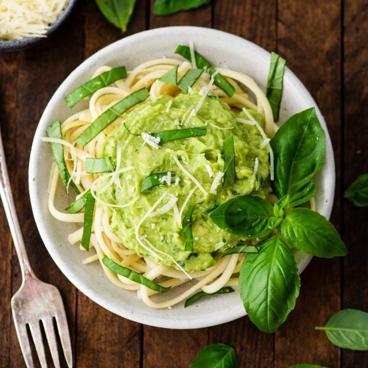 overhead view of a bowl of pasta with Avocado Pasta Sauce on top garnished with fresh basil and parmesan cheese