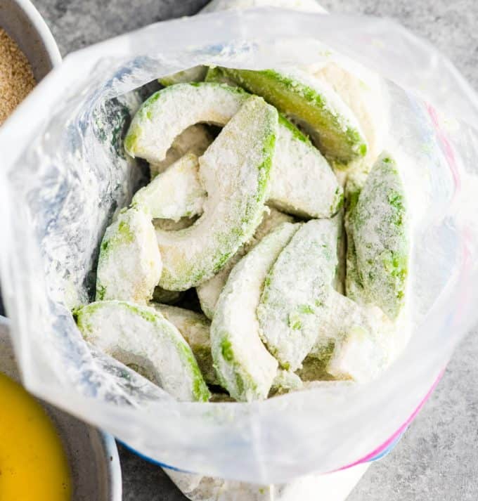 vista dall'alto di fettine di avocado in un sacchetto di plastica dopo che essi sono stati scosso e rivestito con farina nella realizzazione di Forno di Avocado, patate Fritte ricetta